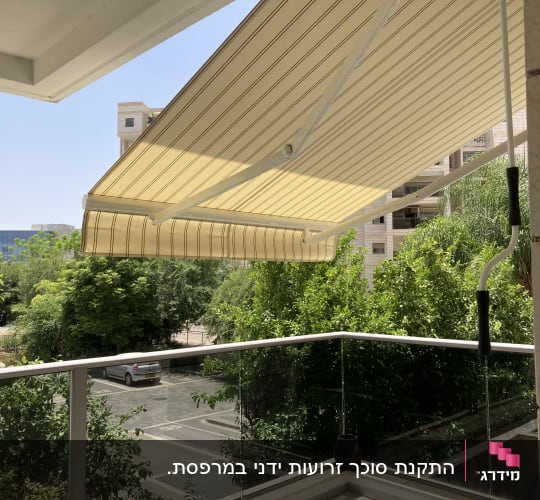 סוכך זרועות מתקפל עם מנואלה ידנית מותקן במרפסת דירה